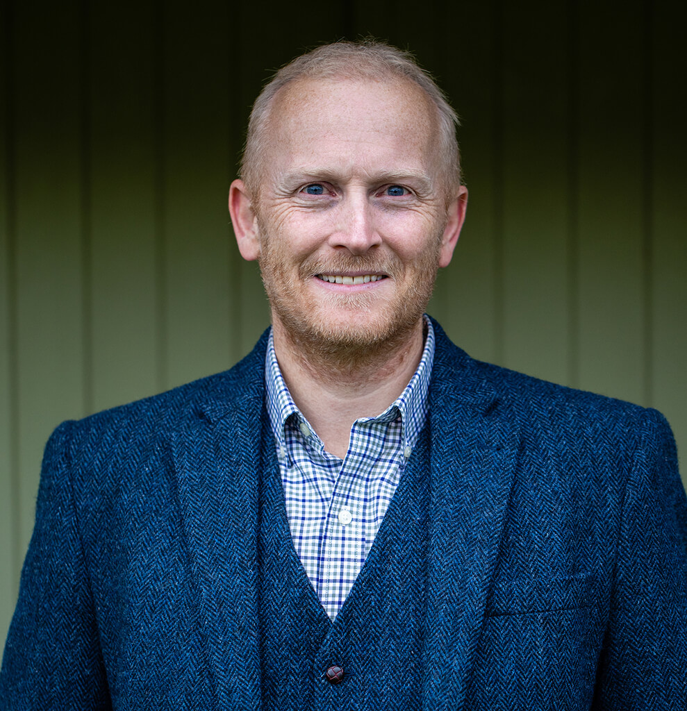 Nick Smith in a blue suit and open-neck shirt