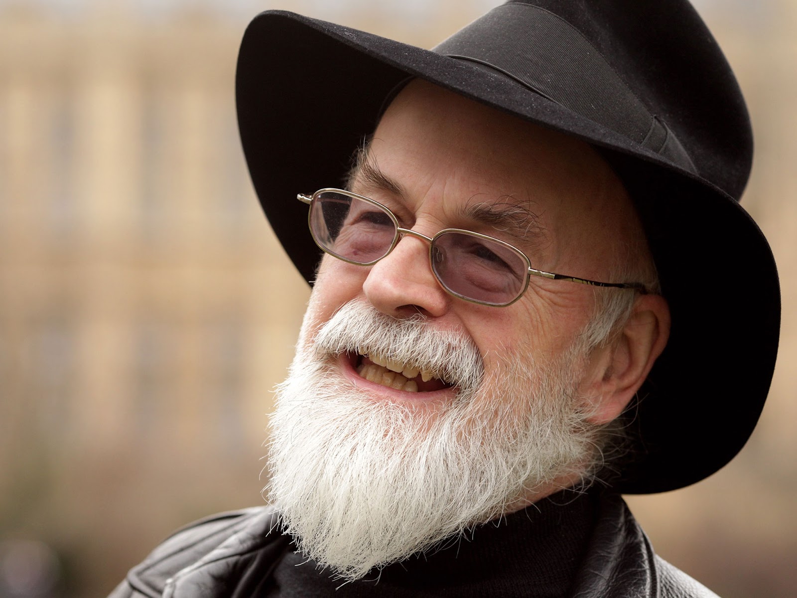 Terry Pratchett in his signature black hat, tinted glasses, and white Father Christmas beard